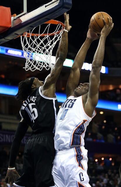 Biyombo, de los Bucks, trata de hacer un mate ante la oposición de Gerald Wallace, de los Nets.