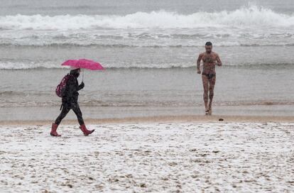 Un bañista sale del agua tras tomarse un baño en la playa de la Concha de San Sebastián, totalmente nevada.