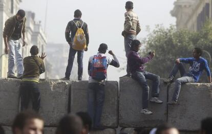 J&oacute;venes se asoman por una de las barricadas erigidas por los militares en los alrededores de la plaza Tahrir.