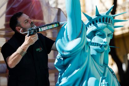 Un artista fallero trabaja en una figura que representa a la estatua de la libertad en uno de los cientos de monumentos falleros, en los que este año las comisiones han invertido cerca de 8,87 millones de euros.