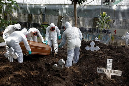 Un grupo de trabajadores mueve el ataúd de una mujer que murió por coronavirus en el cementerio de Santa Tecla (El Salvador).