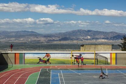 Niños de la barriada juegan en un polideportivo. Al fondo, panorama de Puerto Príncipe, la capital. 