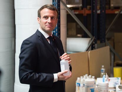 El presidente francés, Emmanuel Macron, sostiene una botella de gel hidroalcohólico durante su visita a una fábrica en Francia que produce mascarillas.