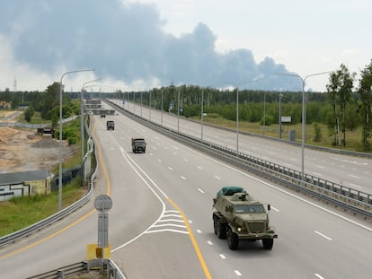 A military column of Wagner private mercenary group drives along M-4 highway, which links the capital Moscow with Russia's southern cities, with smoke from a burning fuel tank at an oil depot seen in the background, near Voronezh, Russia, June 24, 2023.