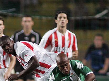 Marcos Dos Santos del Betis lucha por el balón con Olivier Kapo.