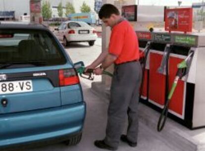 Un empleado de una gasolinera pone carburante en un vehículo.