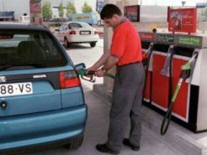 Un empleado de una gasolinera pone carburante en un veh&iacute;culo. 