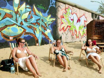 Tres jóvenes disfutan del sol en una terraza de Berlín.