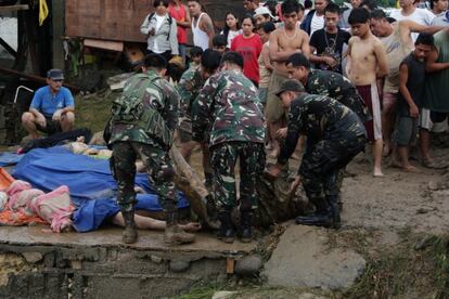 Soldados filipinos juntan cadáveres de fallecidos en las inundaciones al sur del país.