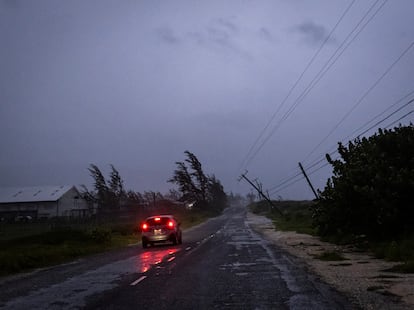A car in the rain drives past a collapsed post as Hurricane Beryl hits the southern coast of the island, in Kingston, Jamaica, July 3, 2024. 