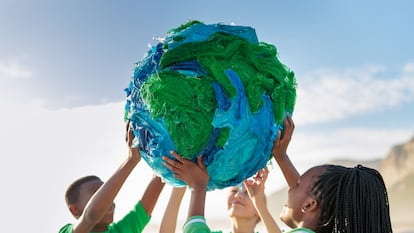 Un grupo de jóvenes activistas por el clima sujeta un globo terráqueo junto a la orilla del mar.