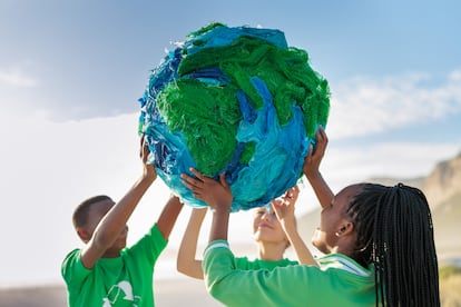 Un grupo de jóvenes activistas por el clima sujeta un globo terráqueo junto a la orilla del mar.