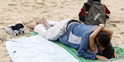 Una pareja de jóvenes se besa en la playa de La Concha.