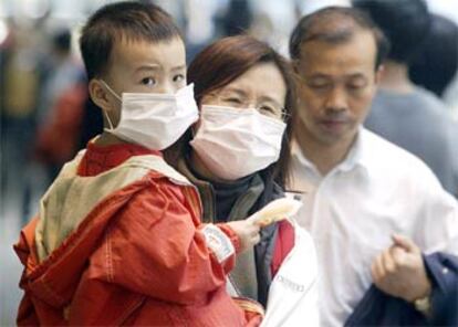 Una mujer y su hijo se protegen con mascarillas en una calle de Hong Kong.
