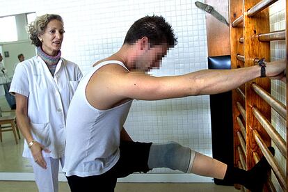 Un paciente realiza sus ejercicios en la sala de rehabilitación del hospital de Bellvitge, en Barcelona, bajo el control de una especialista.