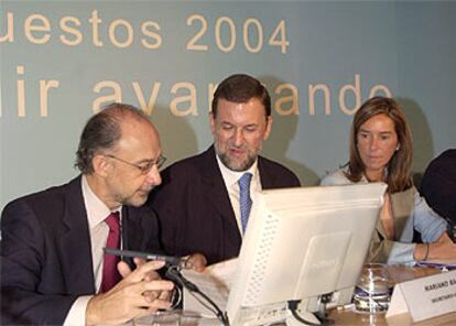 Mariano Rajoy, flanqueado por Cristóbal Montoro y Ana Mato, ayer, en las jornadas de Presupuestos del PP.