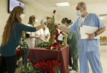 Trabajadores del hospital de Bellvitge reciben las rosas que les han regalado en una iniciativa del gremio de floristerías de Barcelona para homenajear al personal sanitario, durante la celebración de Sant Jordi.