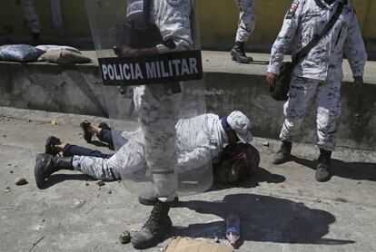 Militar imobiliza um migrante na beira do rio.