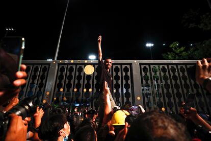 Un activista prodemocracia saluda con tres dedos en alto a los medios a las puertas del Parlamento tailandés en Bangkok este jueves