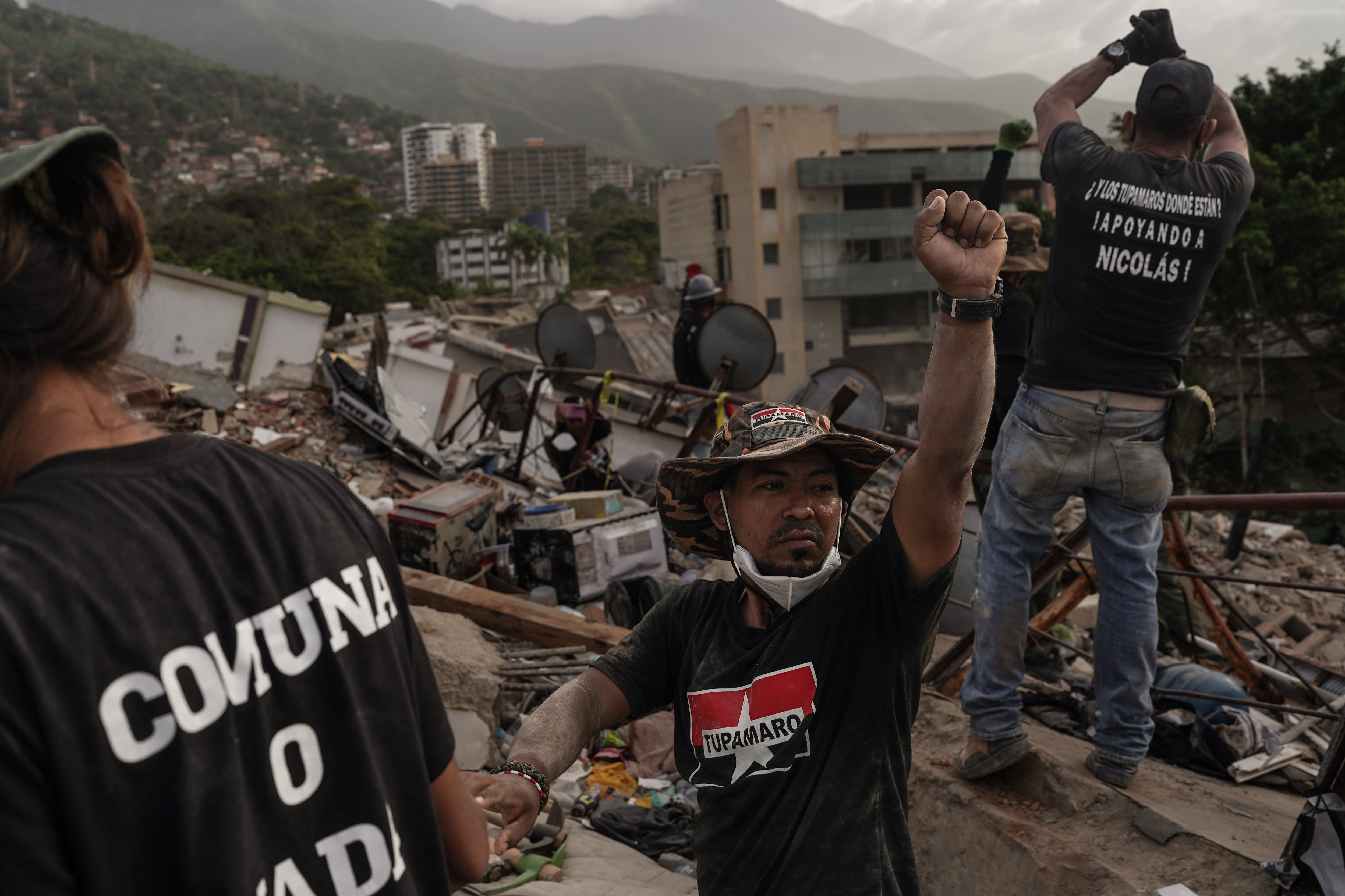Un grupo de volutarios levantan el puño para pedir silencio en búsqueda de sobrevivientes, en La Guaira, el 3 de julio.
