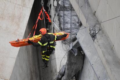 Un trabajador rescata a una persona herida tras el desplome del puente Morandi en Génova (Italia).