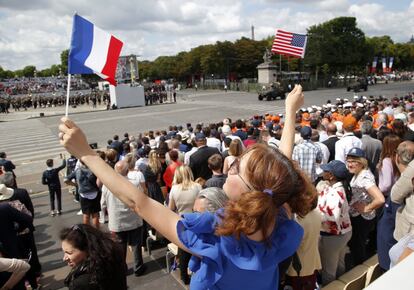 Tras el desfile, Emmanuel Macron viajará a Niza para conmemorar el primer aniversario del ataque terrorista que dejó 86 muertos y 450 heridos. En la foto, una asistente ondea una bandera nacional francesa y una estadounidense durante el desfile militar del Día Nacional de Francia.