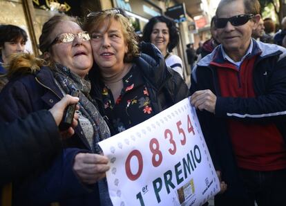 dos mujeres sostiene el número del primer premio del Sorteo del Niño vendido en Torrent (Valencia).