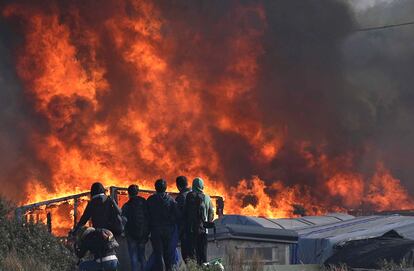 Migrantes miran el incendio de 'La Jungla' de Calais.