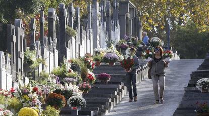 Dos personas acuden con flores al cementerio de Polloe, en San Sebastián.