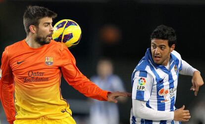 Piqué pelea el balón con el delantero mexicano de la Real Sociedad Carlos Vela.