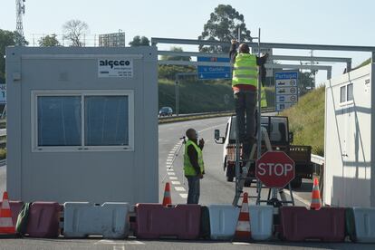 Varios operarios desmantelan un puesto de control tras la reapertura de la frontera entre Portugal y España.