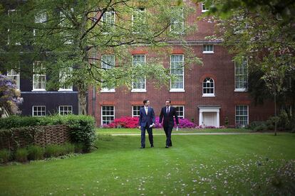 El primer ministro británico, David Cameron y su viceprimer ministro, Nick Glegg, caminan hacia su primera rueda de prensa en el jardín del 10 Downing Street.