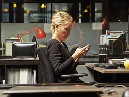 Una mujer consulta su teléfono en el trabajo.