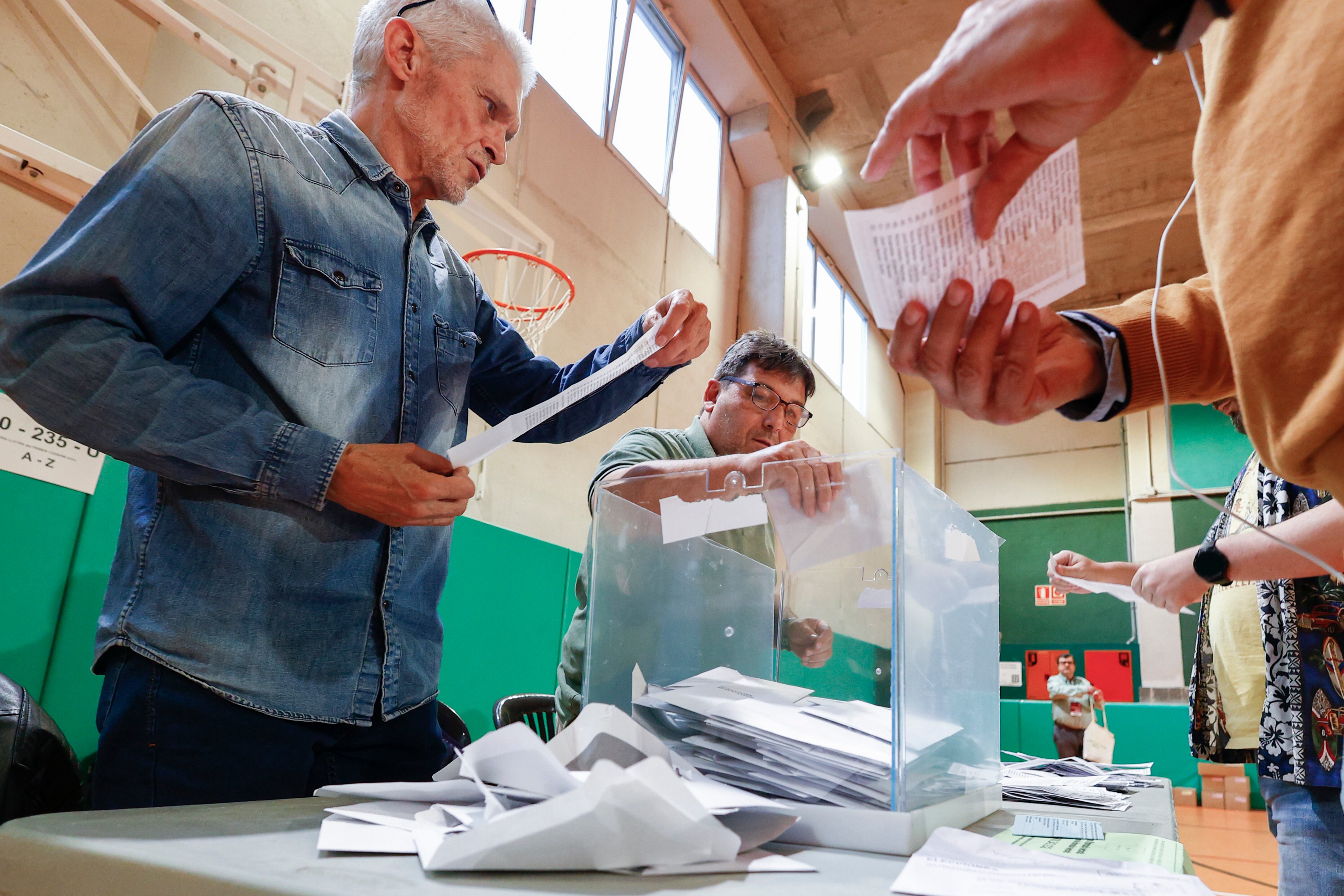  Los miembros de una mesa electoral proceden a la apertura de las urnas para el recuento de votos, tras el cierre de los colegios electorales este domingo.