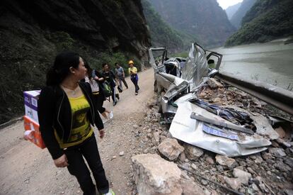 This photo taken on April 21, 2013 shows a woman looking at a damaged car on the road to Baoxing county in the city of Ya'an, southwest China's Sichuan province. Clogged roads, debris and landslides impeded rescuers as they battled to find survivors of a powerful earthquake in mountainous southwest China that has left at least 188 dead