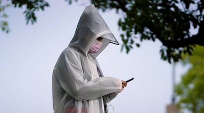 Un hombre con un equipo de protección contra la Covid-19 usa un teléfono móvil.