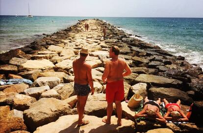 Un grupo de veraneantes toma el sol en el espigón de la playa de El Campello (Alicante).