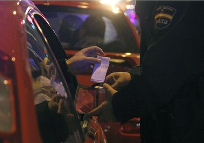 Un agente mira la documentación y la cartera del copiloto de un vehículo para ver si lleva droga.