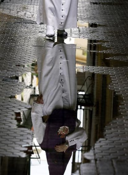 Un penitente camina por una calle encharcada en Sevilla.