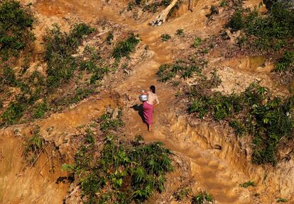 Una mujer rohingya transporta un recipiente lleno de agua mientras camina cuesta arriba hacia su refugio temporal del campo de refugiados de Palongkhali, cerca de Cox's Bazar (Bangladés).