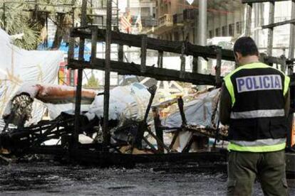 Un policía toma nota de los destrozos causados por en la falla del Ayuntamiento de Valencia.