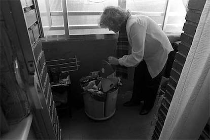 Una mujer, junto a un cubo de recogida selectiva de basura.