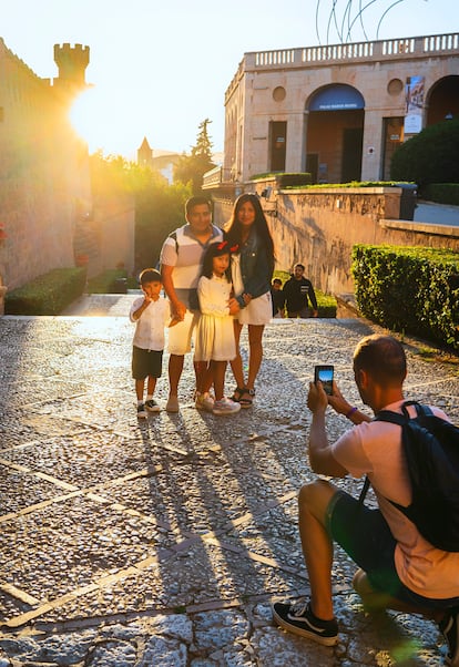 Un mallorquín retrata a una familia de visitantes en los alrededores de la catedral de Palma.