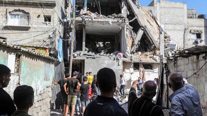 Residentes palestinos observan los restos de un edificio destruido en un ataque israelí en el campo de refugiados de Nuseirat, en Gaza.
