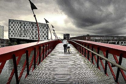 Escultórico puente rojo entre Sporenburg y Borneo, con el edificio de apartamentos y oficinas La Ballena al fondo, proyectado por Erick van Egeraat y finalizado por Frits van Dongen.