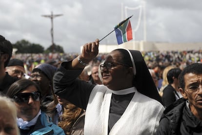 Una monja con una bandera sudafricana se protege del sol.