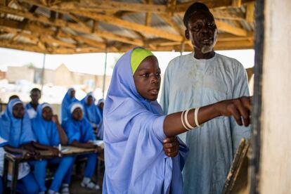 Hawa, de 12 años, señala la pizarra en la escuela primaria Sabo Garawi en Gwoza, noreste de Nigeria, mientras su maestro observa. Cuando Gwoza fue tomado por milicias hace cuatro años, Hawa huyó de la ciudad y pasó tres meses escondida hasta que la ciudad fue recuperada por el ejército nigeriano. Su padre fue asesinado durante o después del ataque, la joven no sabe con certeza cuándo. "Las milicias destruyeron todo en la escuela", cuenta Hawa.