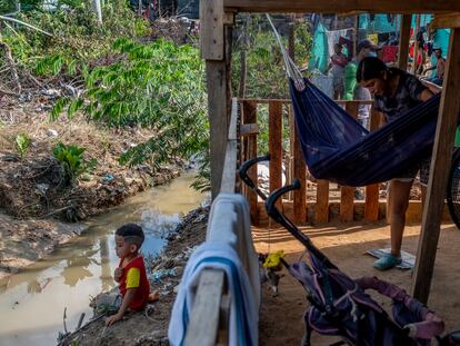 La venezolana Alexandra Andrade, de 16 años, mece a su niño en el asentamiento irregular del 12 de septiembre, en Tibú, frente al caño de aguas negras que rodea su casa.