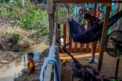 La venezolana Alexandra Andrade, de 16 años, mece a su niño en el asentamiento irregular del 12 de septiembre, en Tibú, frente al caño de aguas negras que rodea su casa.