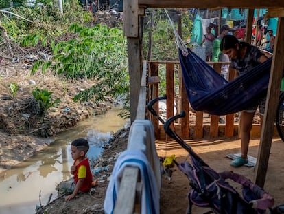 La venezolana Alexandra Andrade, de 16 años, mece a su niño en el asentamiento irregular del 12 de septiembre, en Tibú, frente al caño de aguas negras que rodea su casa.